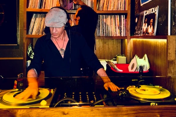 DJ Turmix mixing records in front of a wall of vinyl
